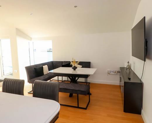 Open-plan living room with balcony and sea views at Sea Breeze Retreat Pwllheli